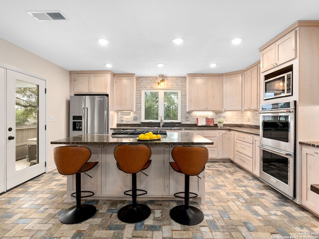 kitchen featuring dark stone counters, stainless steel appliances, a kitchen island, and visible vents