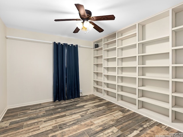 empty room with dark wood-style flooring, a ceiling fan, and baseboards