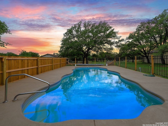 pool at dusk with a patio area, a fenced backyard, and a fenced in pool