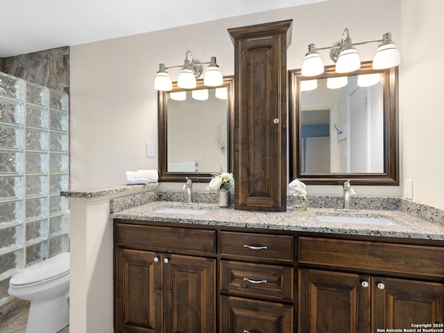 bathroom featuring double vanity, toilet, and a sink