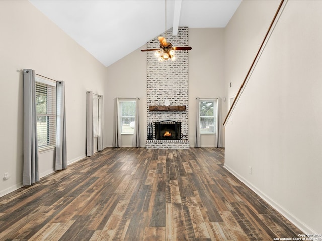 unfurnished living room featuring dark wood-style floors, a brick fireplace, a healthy amount of sunlight, and beam ceiling