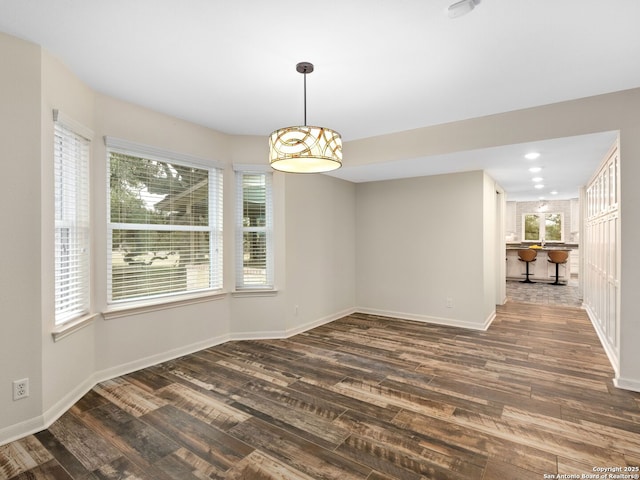 unfurnished dining area with dark wood-type flooring, recessed lighting, and baseboards