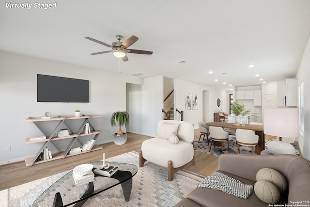 living room with baseboards, a ceiling fan, stairway, light wood-style floors, and recessed lighting