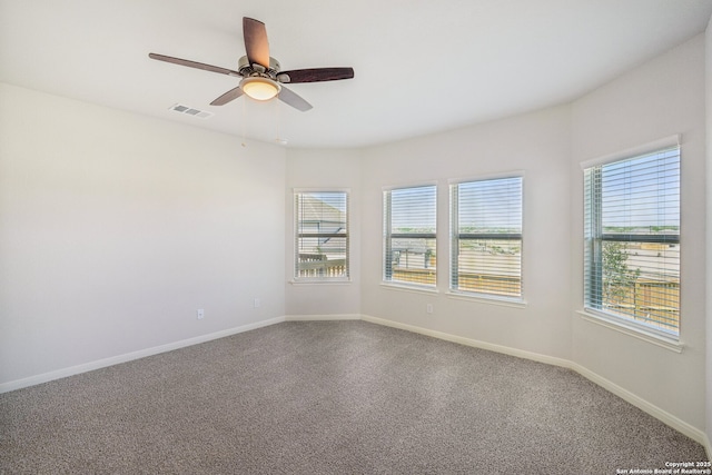 carpeted spare room featuring a wealth of natural light, visible vents, and baseboards