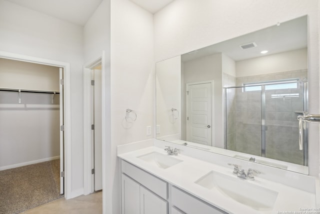 bathroom with a stall shower, a walk in closet, visible vents, and a sink