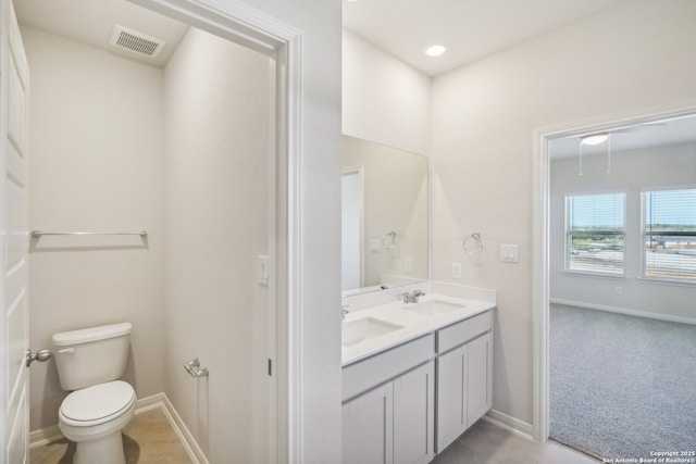 bathroom featuring toilet, double vanity, a sink, and visible vents