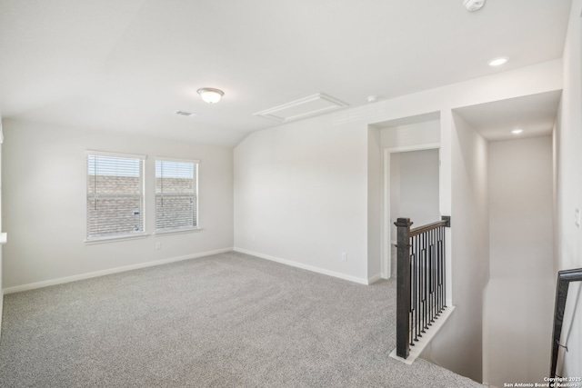 empty room featuring lofted ceiling, recessed lighting, carpet flooring, baseboards, and attic access