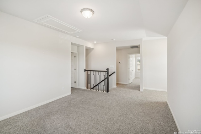 spare room with attic access, light colored carpet, visible vents, and baseboards