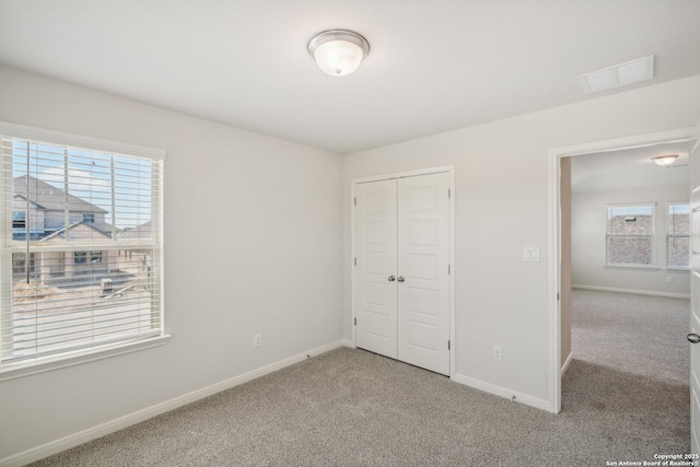 unfurnished bedroom featuring light carpet, baseboards, and multiple windows