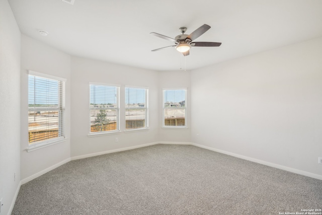 carpeted spare room featuring baseboards and a ceiling fan