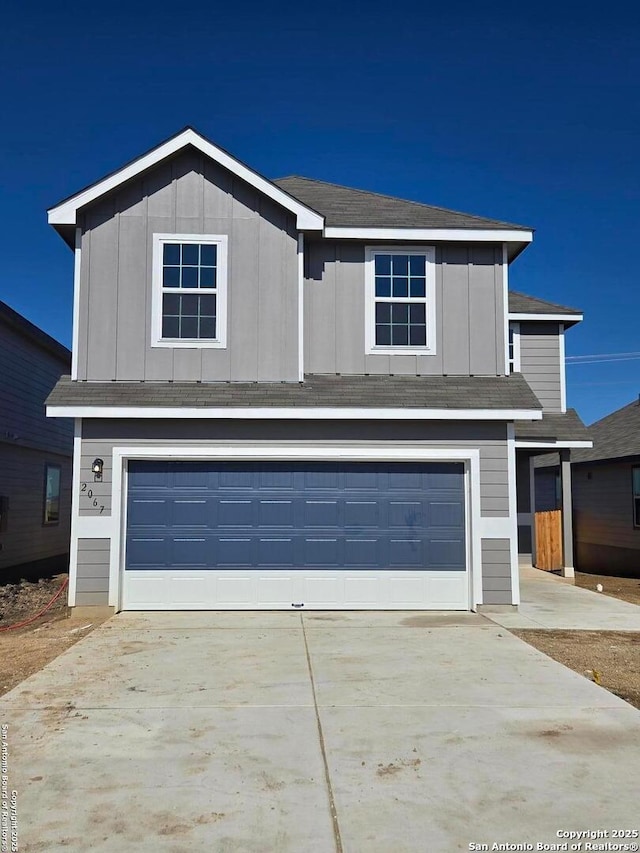 traditional-style home featuring a garage, driveway, and board and batten siding