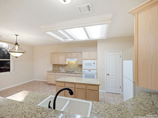 kitchen featuring under cabinet range hood, white appliances, a sink, visible vents, and light brown cabinetry