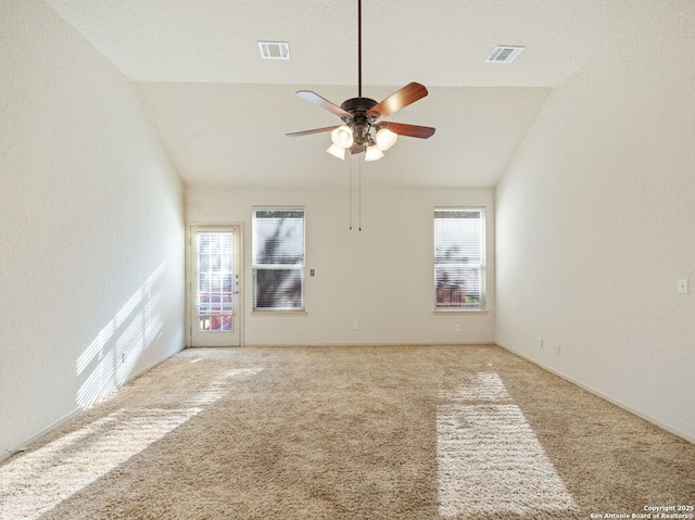 empty room with a wealth of natural light, light colored carpet, and vaulted ceiling