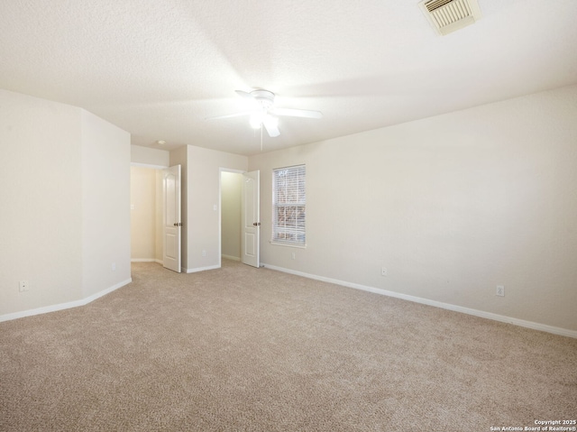 unfurnished room featuring light colored carpet, visible vents, a ceiling fan, a textured ceiling, and baseboards