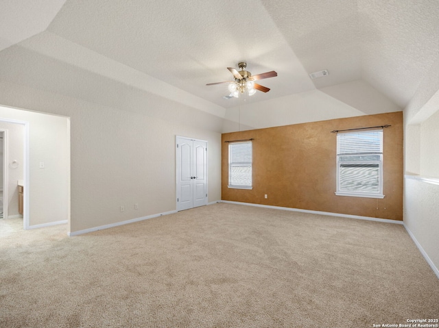 carpeted spare room with a textured ceiling, visible vents, baseboards, vaulted ceiling, and a ceiling fan