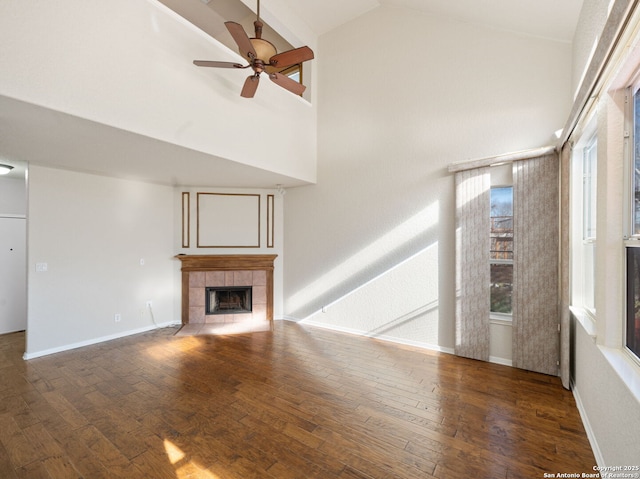 unfurnished living room with high vaulted ceiling, a ceiling fan, dark wood finished floors, and a tiled fireplace