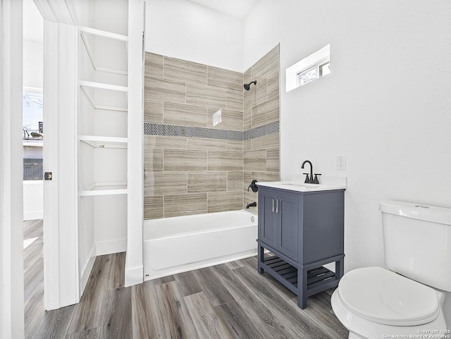 full bath featuring toilet, wood finished floors, vanity, a wealth of natural light, and washtub / shower combination