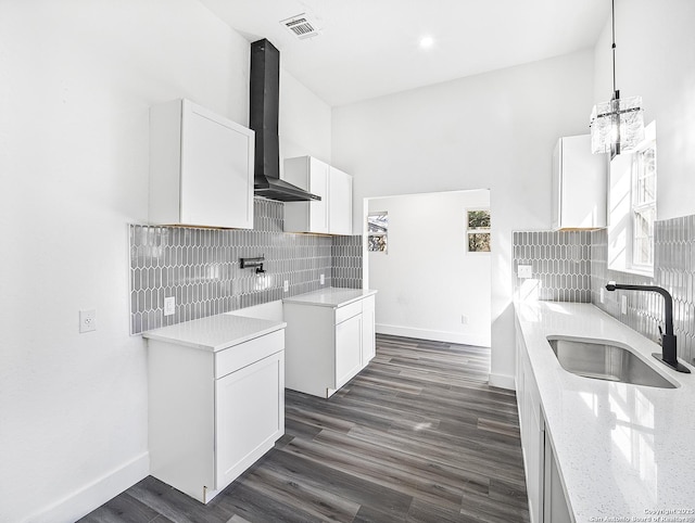 kitchen featuring dark wood-type flooring, white cabinets, a sink, and wall chimney range hood