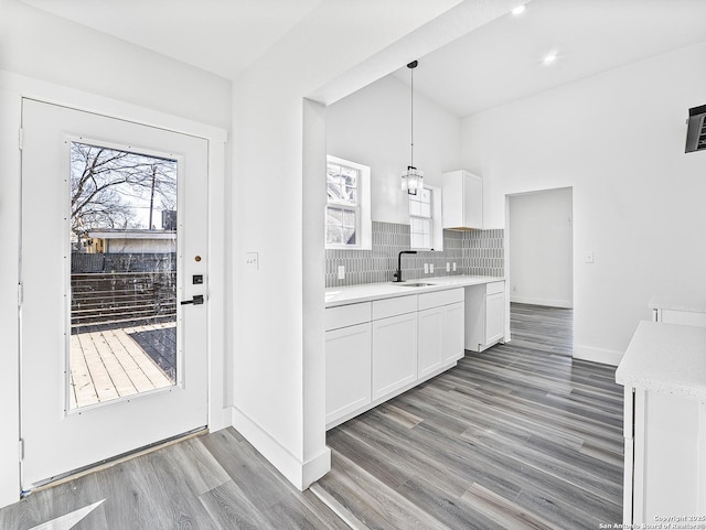 kitchen with hanging light fixtures, white cabinets, light countertops, and a sink