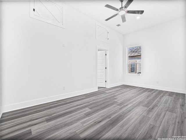 spare room with a ceiling fan, visible vents, baseboards, and wood finished floors