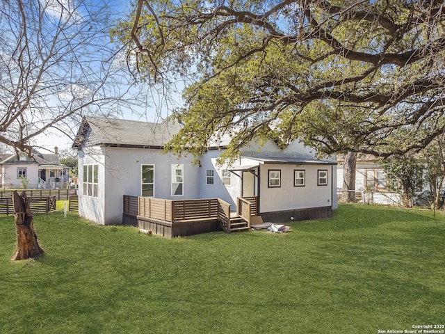 back of house with a lawn, fence, and stucco siding