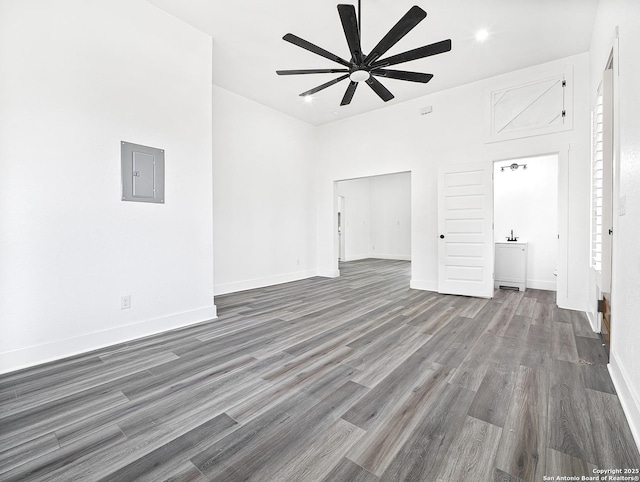 spare room with ceiling fan, electric panel, baseboards, and dark wood-style flooring