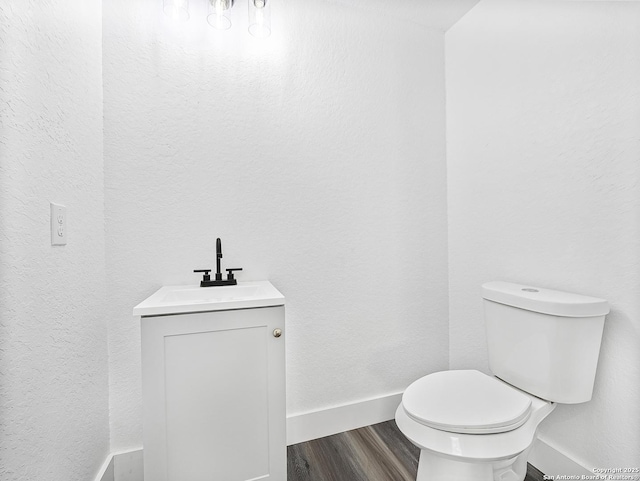bathroom with baseboards, vanity, toilet, and wood finished floors