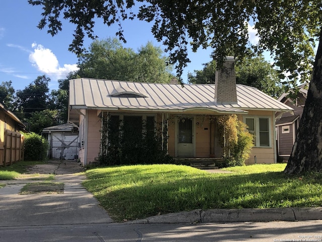 view of front of house with a front yard, a standing seam roof, metal roof, and a chimney