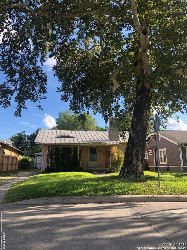 view of front of home featuring a standing seam roof, metal roof, a front lawn, and fence