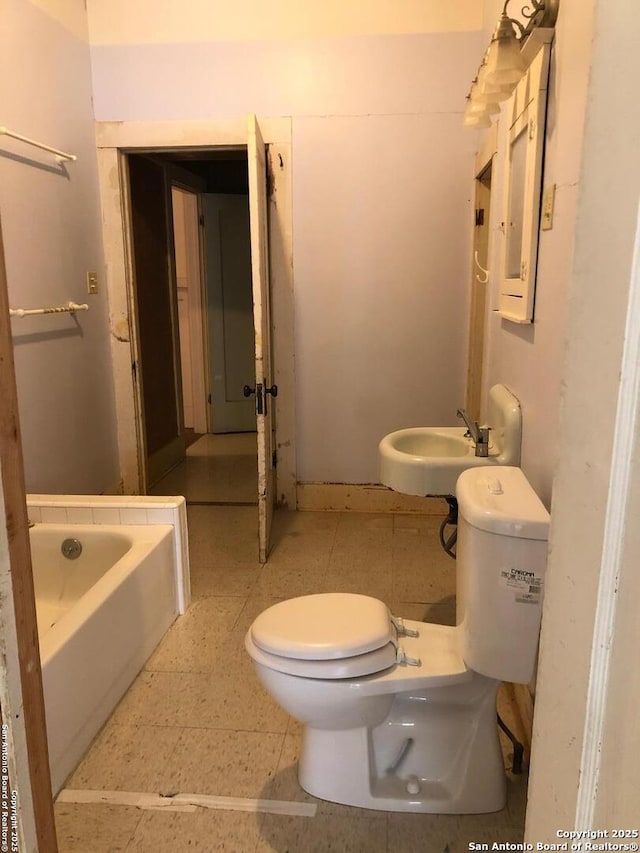 bathroom featuring a sink, toilet, and a bath