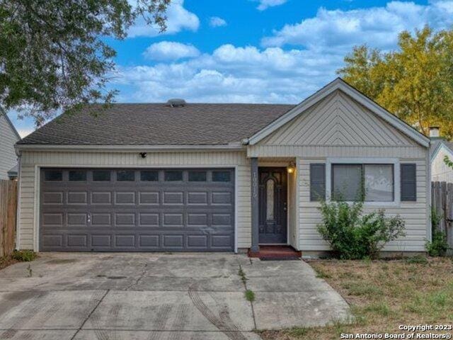 ranch-style house with a garage, driveway, and fence