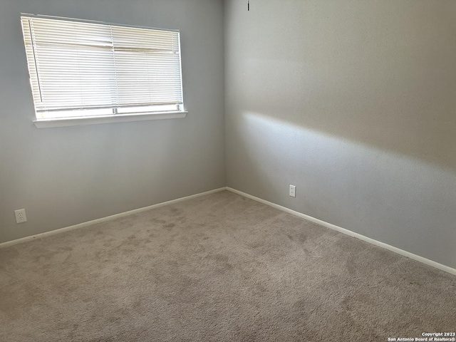 spare room featuring carpet floors and baseboards