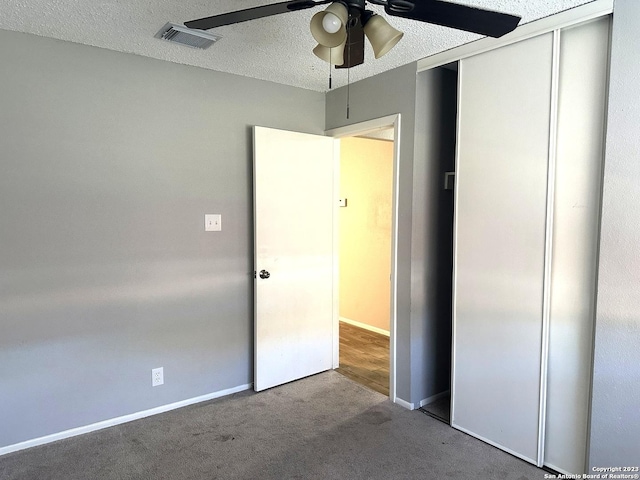 unfurnished bedroom featuring a textured ceiling, carpet flooring, visible vents, baseboards, and a closet