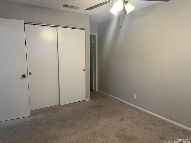 unfurnished bedroom with visible vents, light colored carpet, ceiling fan, a textured ceiling, and a closet