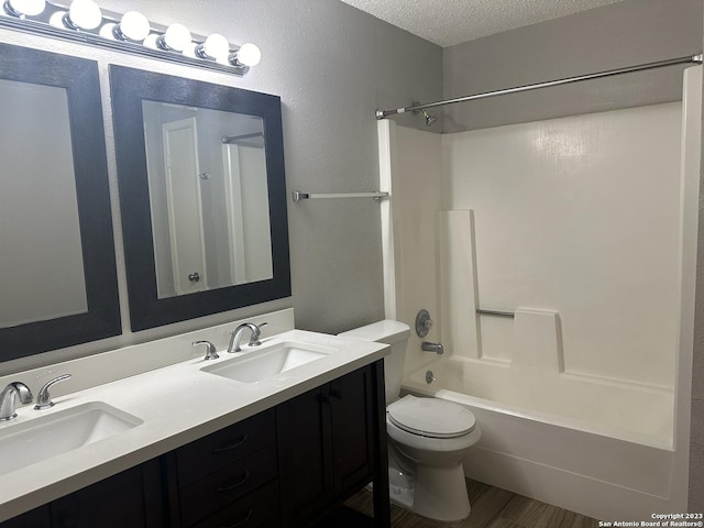 full bath with tub / shower combination, a sink, a textured ceiling, and toilet