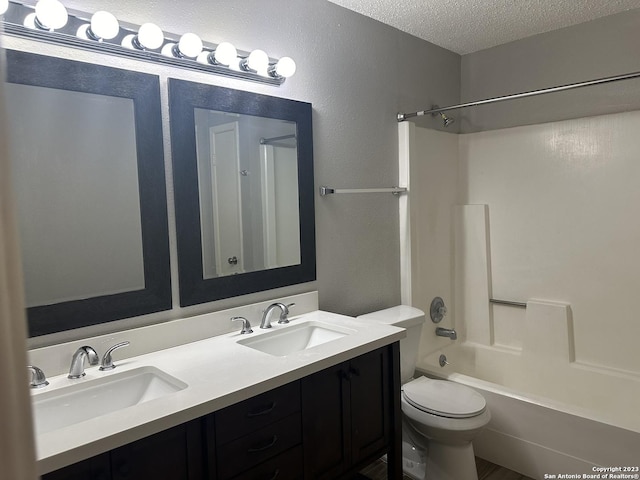 bathroom featuring a textured ceiling,  shower combination, double vanity, and a sink