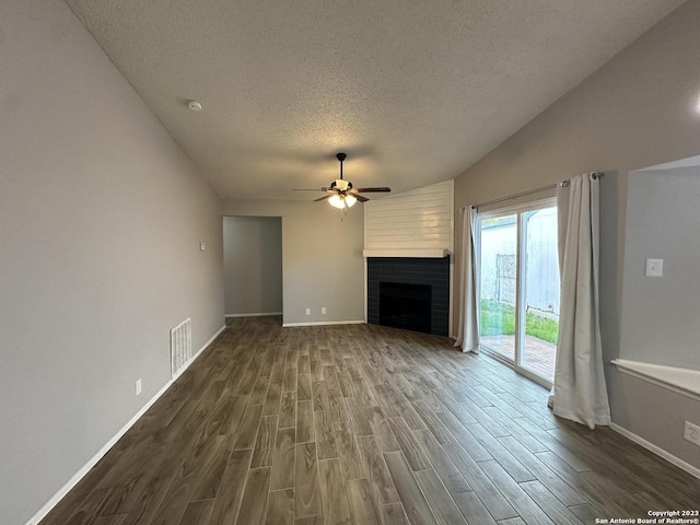 unfurnished living room featuring dark wood-style flooring, a fireplace, visible vents, ceiling fan, and a textured ceiling