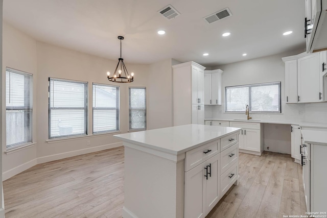 kitchen with a kitchen island, visible vents, light countertops, and a sink