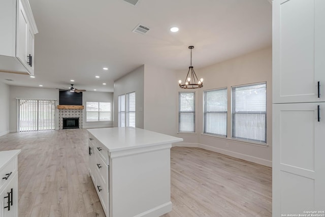 kitchen with a kitchen island, white cabinetry, open floor plan, and light countertops