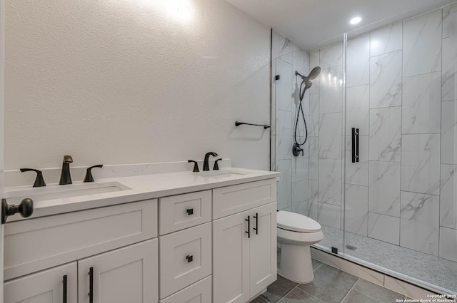 full bath featuring toilet, a sink, a marble finish shower, and double vanity