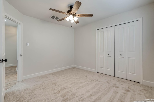 unfurnished bedroom featuring baseboards, a closet, visible vents, and light colored carpet