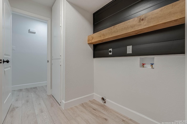 clothes washing area featuring light wood finished floors, baseboards, and washer hookup