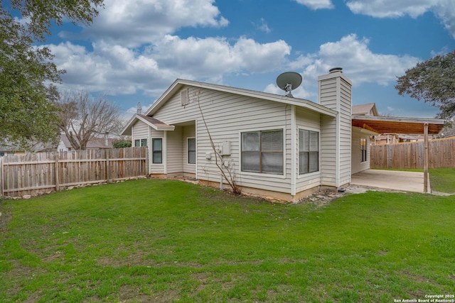 back of property featuring a yard, a chimney, a patio area, and fence