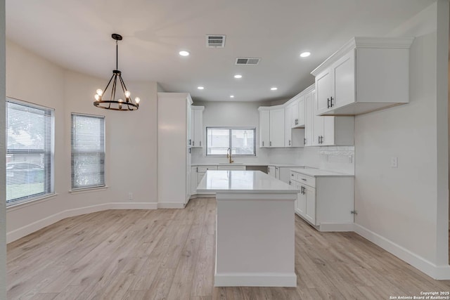 kitchen featuring a center island, light countertops, visible vents, and white cabinetry