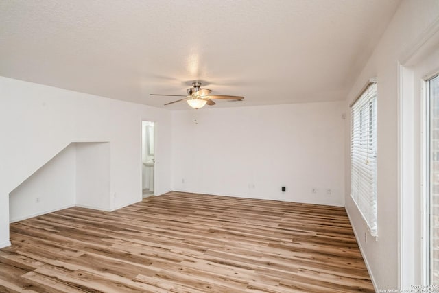 unfurnished room with ceiling fan, light wood finished floors, and a textured ceiling