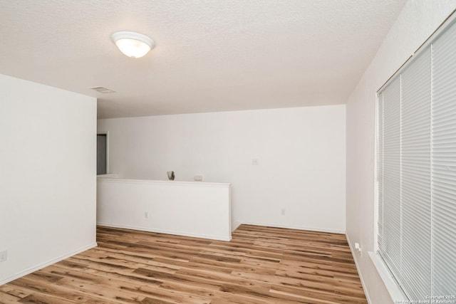 empty room with a textured ceiling and wood finished floors