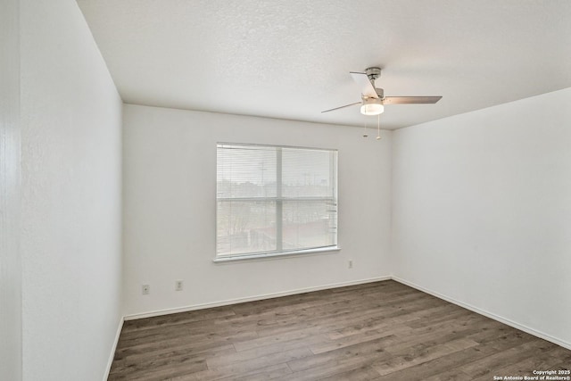 empty room featuring baseboards, a ceiling fan, dark wood finished floors, and a textured ceiling