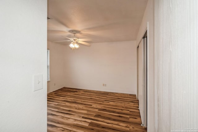 empty room with dark wood-style flooring, ceiling fan, and baseboards