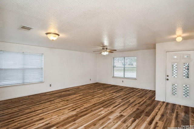 foyer entrance featuring a ceiling fan, visible vents, dark wood finished floors, and a textured ceiling