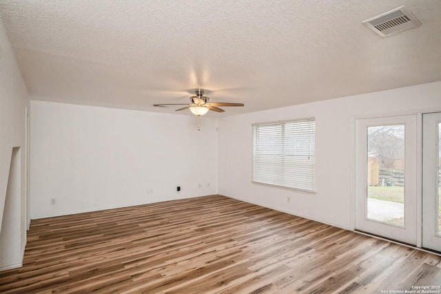 unfurnished room featuring visible vents, plenty of natural light, and wood finished floors